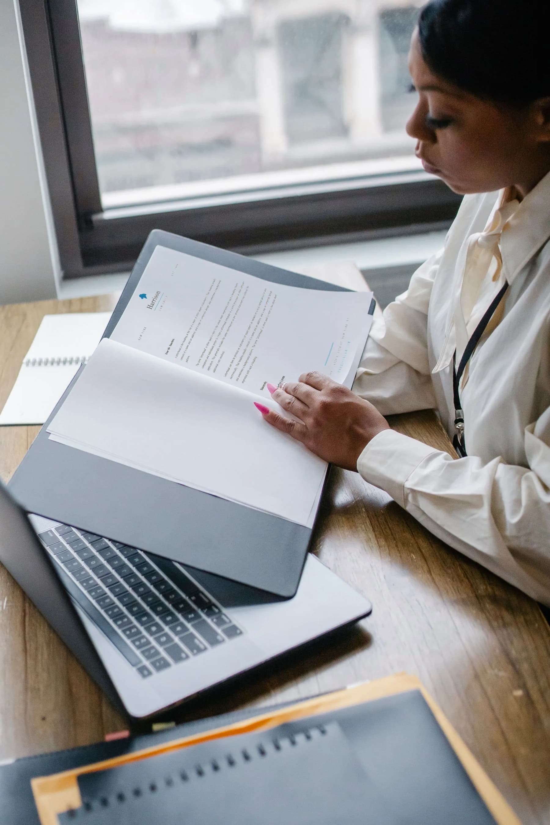 Financial services professional reviewing documents beside a laptop